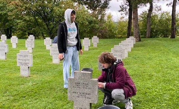 Zwei Jugendliche reinigen Gräber.