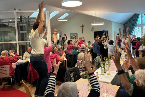 Viele sitzende und tanzende Personen in einem großen Raum.