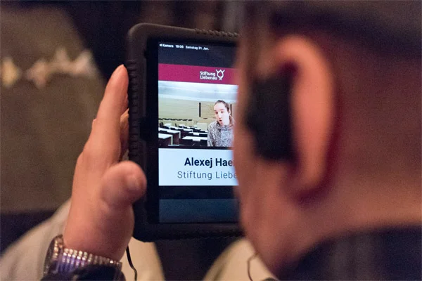 Wahlveranstaltung Eine Person schaut auf ein Tablet.