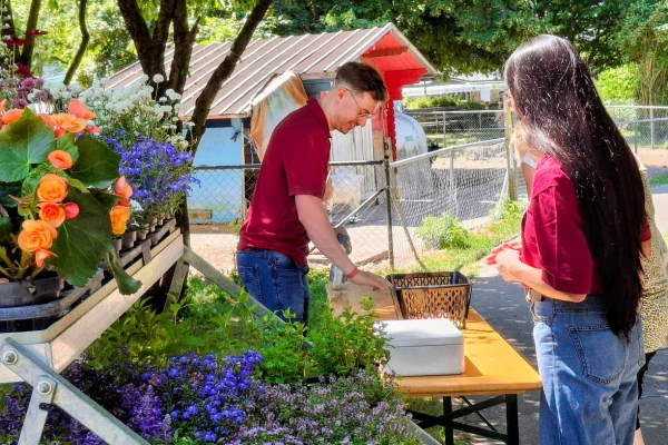 Ein Mann und eine Frau stehen vor einem kleinen Blumenstand.