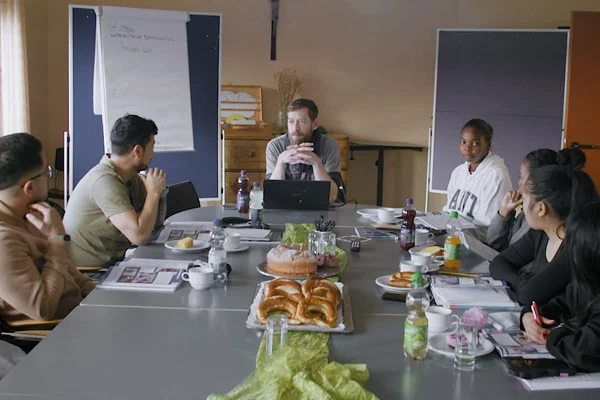 Mehrere Personen sitzen an einem Tisch und unterhalten sich.