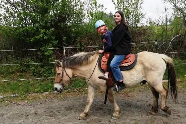 Das Bild zeigt eine Frau und ein Kind auf einem Pferd