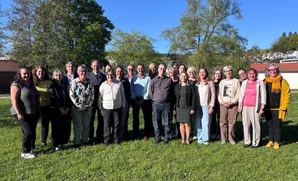 Eine Personengruppe aufgestellt zu einem Gruppenfoto in einer Wiese.