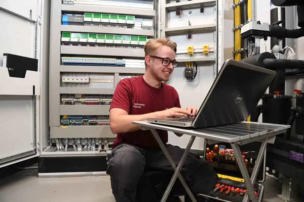 Das Bild zeigt einen Mann der an einem Laptop arbeitet