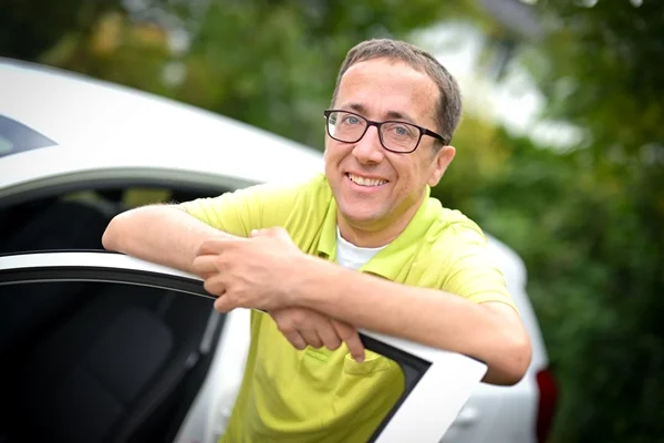 Das Bild zeigt einen Mann an einer offenen Autotür