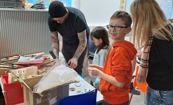 Das Bild zeigt drei Kinder und einen Mann beim Basteln