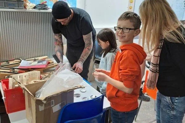Das Bild zeigt drei Kinder und einen Mann beim Basteln