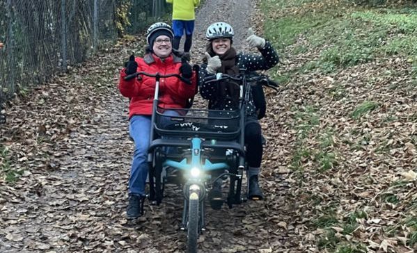 Zwei Damen sitzen in einem Doppelsitzer- Dreirad