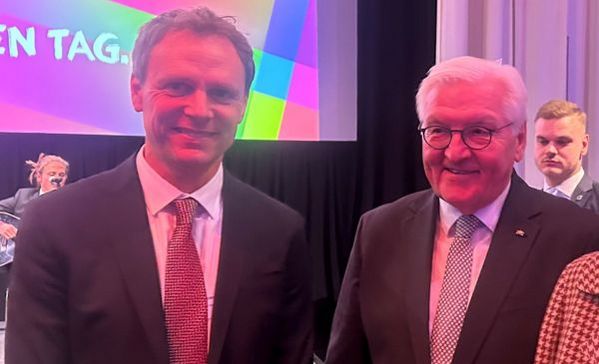 Zwei Männer im Anzug stehen nebeneinander und schauen in die Kamera.