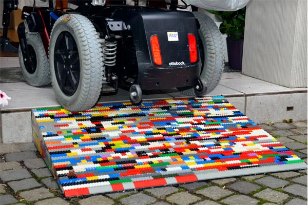legorampen für elektrorollstühle in bad waldsee das bild zeigt einen elektrorollstuhl, der über eine bunte lego-rampe eine stufe hochfährt
