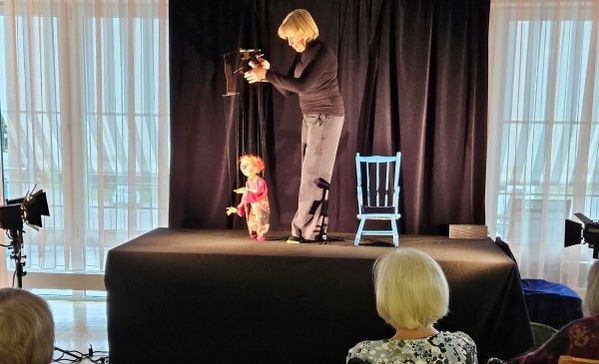 Das Bild zeigt Christine Kümmel mit einer Marionette auf der Bühne im Haus Martinus.