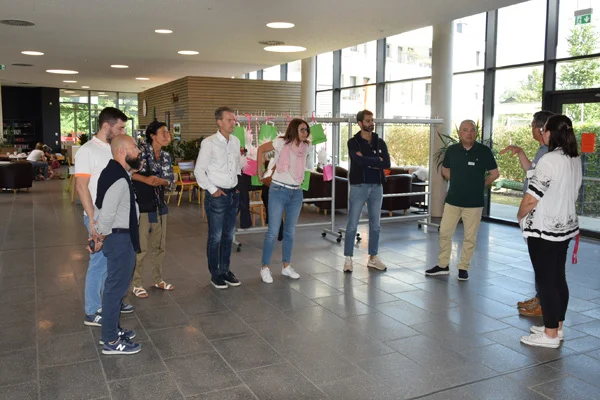 Gäste aus Italien informieren sich über die Lebensräume. bei einem fachaustausch der stiftung liebenau mit internationalen gästen werden auch die lebensräume besichtigt. das foto zeigt eine gruppe von menschen im halbkreis beim austausch.