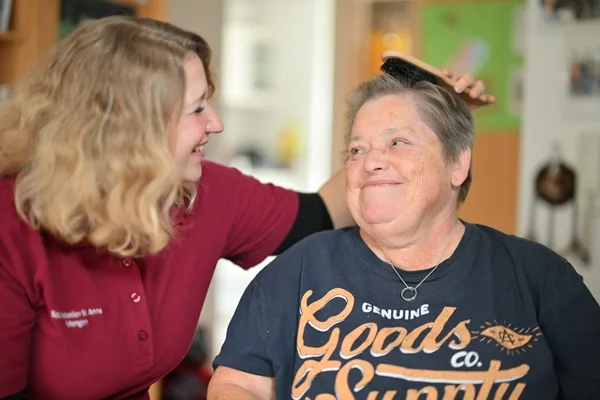 Das Bild zeigt eine Frau, die einer anderen Frau die Haare kämmt