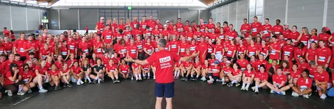 Eine große Gruppe bei einem Gruppenfoto. Alle tragen rote Tshirts.