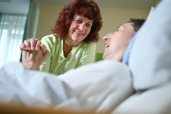 Franziskuszentrum Das Bild zeigt eine Pflegerin bei einem Mann im Bett