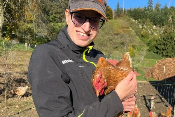 Ein tierisches (Arbeits-) Vergnügen Das Bild zeigt eine jungen Frau mit einem Huhn auf dem Arm