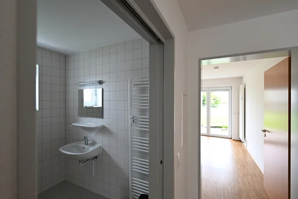 Wohnanlage Berg Das Bild zeigt den Zugang zu Bad und Zimmer in einer leeren Wohnung