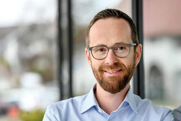 Ein Portraitfoto eines Manns, der in die Kamera lächelt.