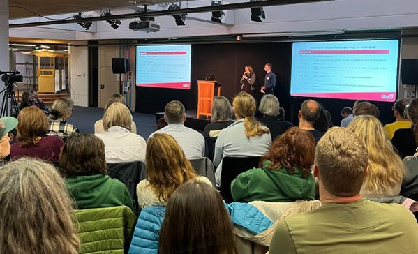 Fachtag Zwei Personen tragen etwas vor und viele Personen hören zu.