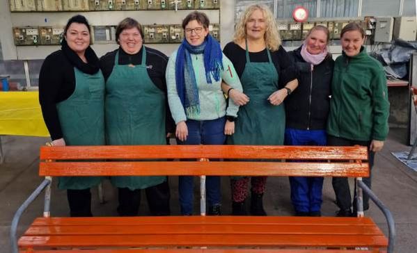 Das Bild zeigt die Frauenbeauftragten der Liebenauer Arbeitswelten vor einer orange gestrichenen Bank