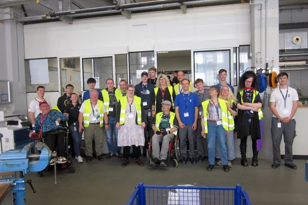 Gruppenbild verschiedener Personen in Warnwesten in einem Gebäude.