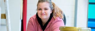 Das Bild zeigt eine junge Frau in einer Malerwerkstatt