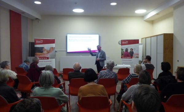 Eine Menschengruppe hört einem Vortrag zu