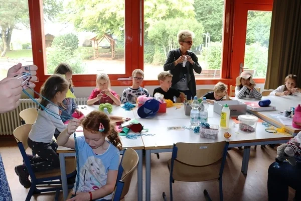 Das Bild zeigt eine Gruppe Kinder beim Basteln an einem Tisch