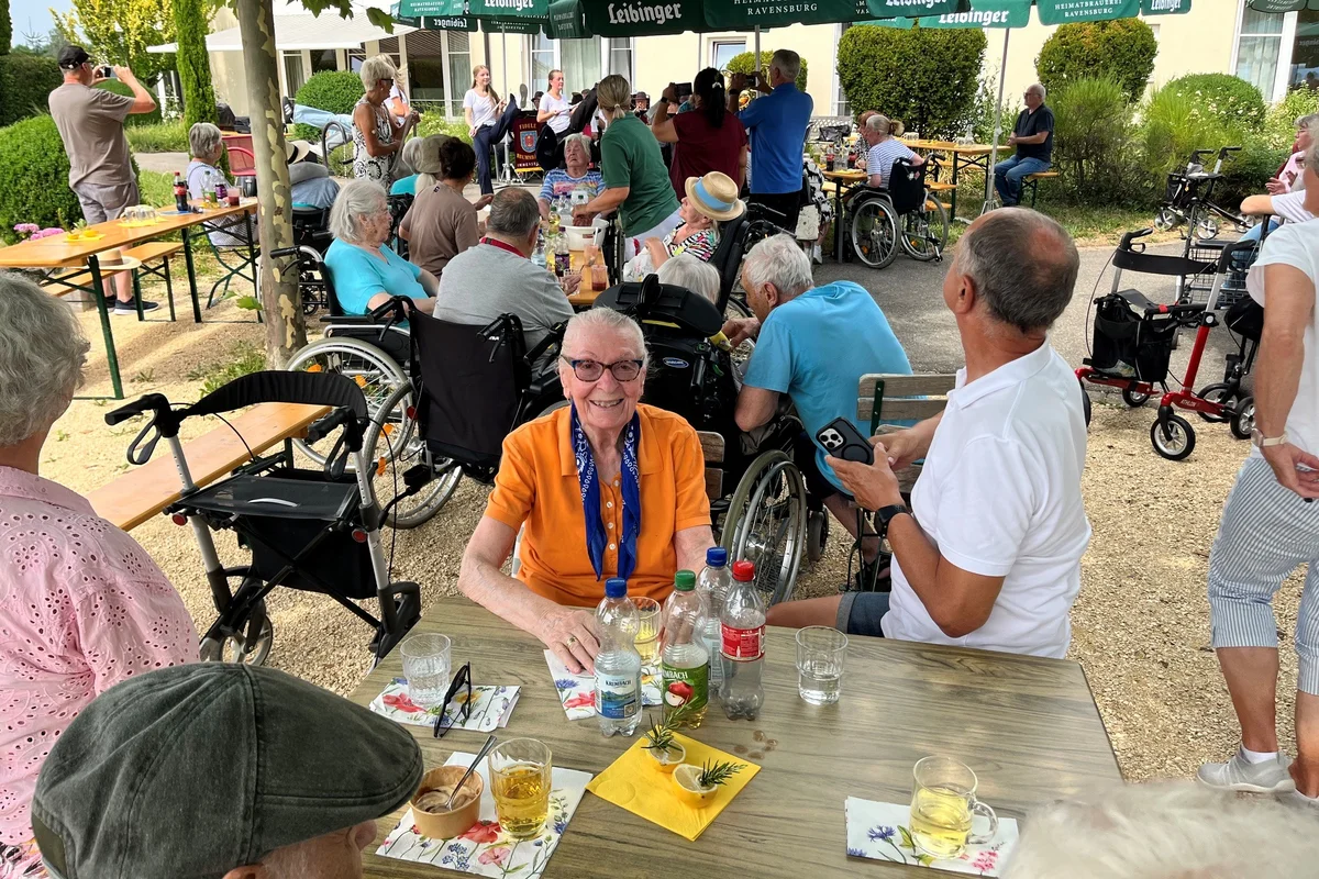 Sommerfest Viele Personen bei einem Sommerfest sitzen unter Schirmen.