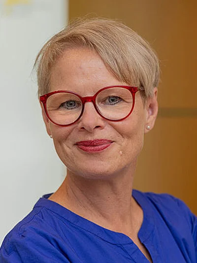 Aufsichtsrätin Portraitfoto einer Frau mit kurzen blonden Haaren und einer roten Brille.