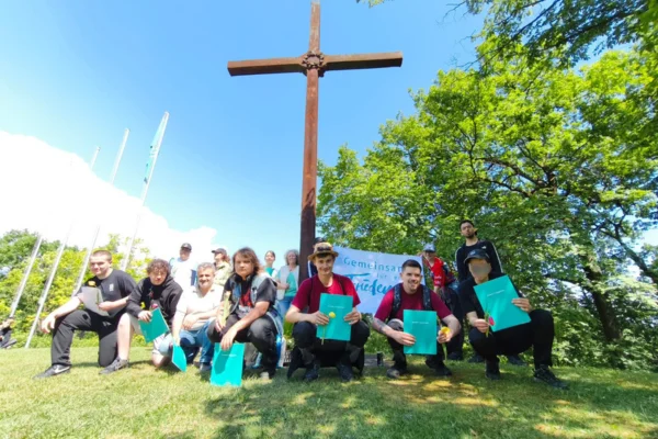 Eine Gruppe von Personen mit Zertifikaten vor einem Kreuz.