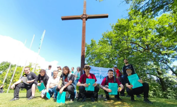 Eine Gruppe von Personen mit Zertifikaten vor einem Kreuz.