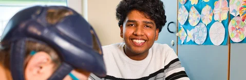 Das Bild zeigt einen jungen Mann mit einem Klienten in einem Raum