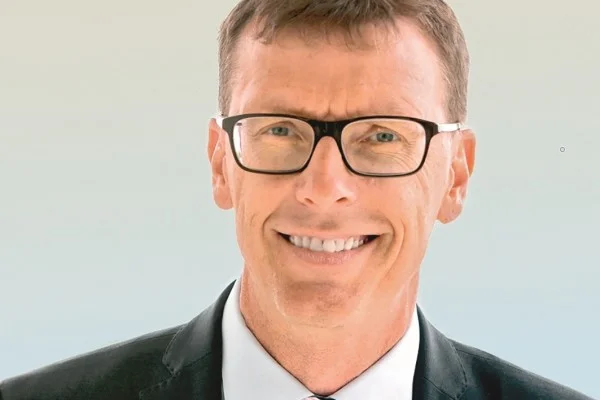 Andreas Schmid, Beauftragter für Ehrenamt und bürgerschaftliches Engagement bei der Stiftung Liebenau. Das Bild zeigt einen Mann mit Brille und im Anzug der in die Kamera schaut und lacht.