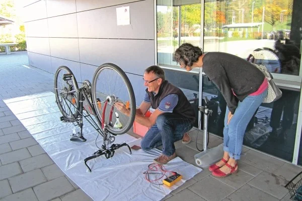 Das Bild zeigt zwei Personen die gerade ein Fahrrad reparieren