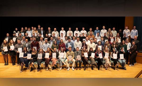 Ein Gruppenbild mit sehr vielen Personen mit Zeugnissen in der Hand.