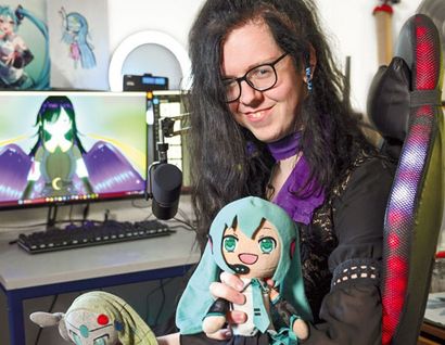 das foto zeigt einen menschen mit einschränkung mit anime-puppen vor einem bildschirm, der eine anime-zeichnung zeigt