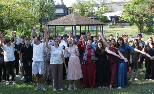 Gruppenbild vieler jubelnder Menschen auf einer Wiese.