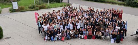 Das Foto zeigt eine große Gruppe winkender, junger Menschen, die mit ihrer Ausbildung beginnen.