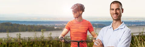 Im Vordergrund ist ein Mitarbeiter in Arbeitskleidung zu sehen. Im Hintergrund ist der gleiche Mitarbeiter beim Fahrrad fahren zu sehen. 