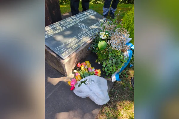 Kriegsgräber Ein Grabstein mit Blumensträußen.