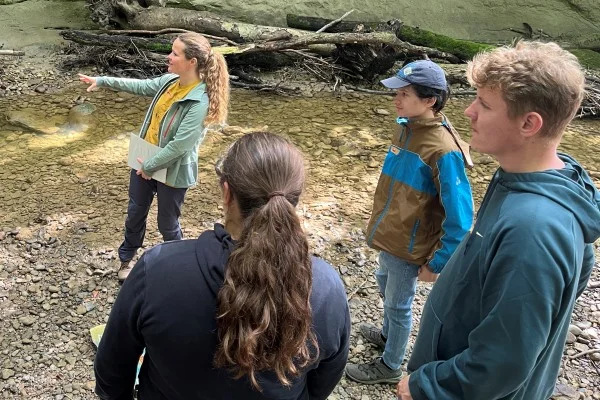 Simone Krafscik erklärt, worum es bei der nächsten Aufgabe geht. Das Bild zeigt eine Gruppe im Wald