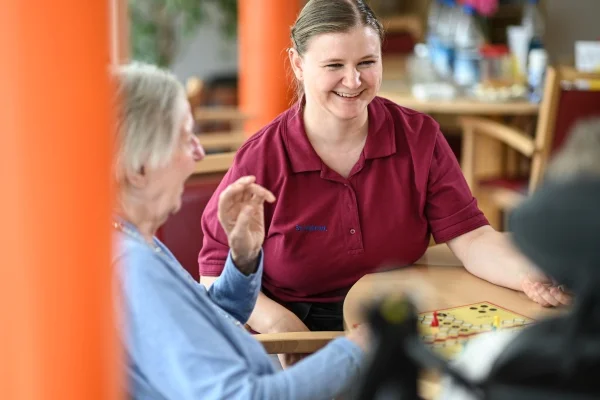Das Bild zeigt eine Pflegerin mit einer älteren Dame beim Brettspiel