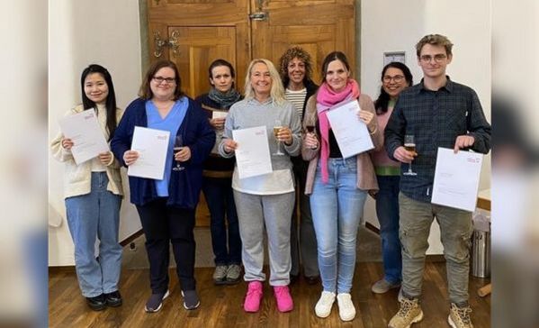 Eine Menschengruppe hält Urkunden in der Hand und lächelt in die Kamera