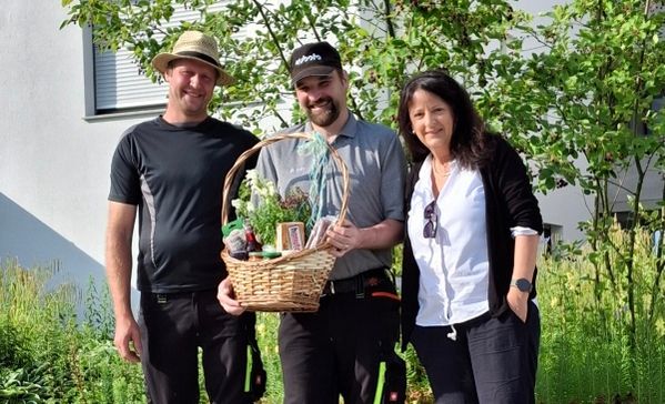 Das Bild zeigt drei Personen mit einem Geschenkkorb