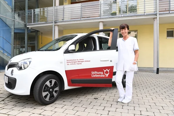 Das Bild zeigt eine Frau vor einem Auto