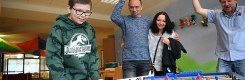 Das Bild zeigt Eltern und Kinder beim Flipper spielen