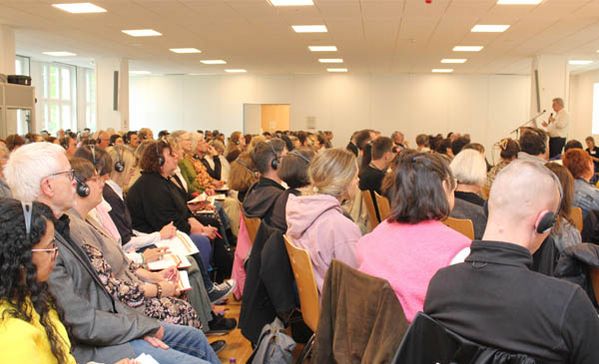 Sehr viele Personen sitzen im Publikum bei einem Vortrag.