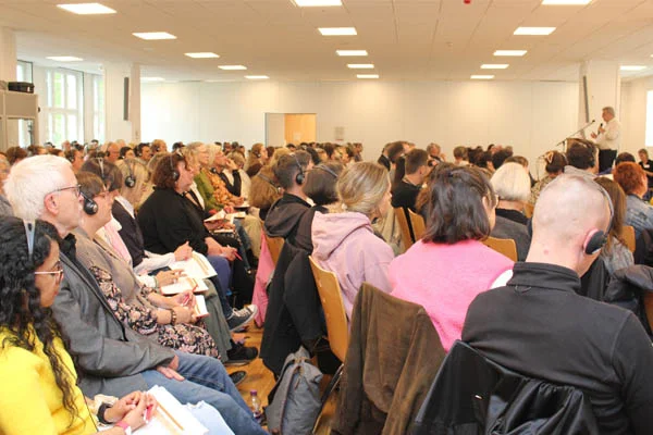 Fachtag Sehr viele Personen sitzen im Publikum bei einem Vortrag.