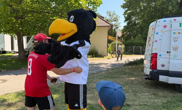 Das Maskottchen begrüßt einen Bewohner.